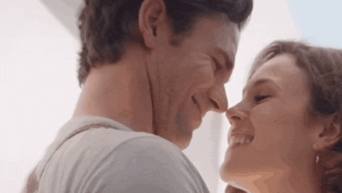 a man and woman are touching their noses and smiling .