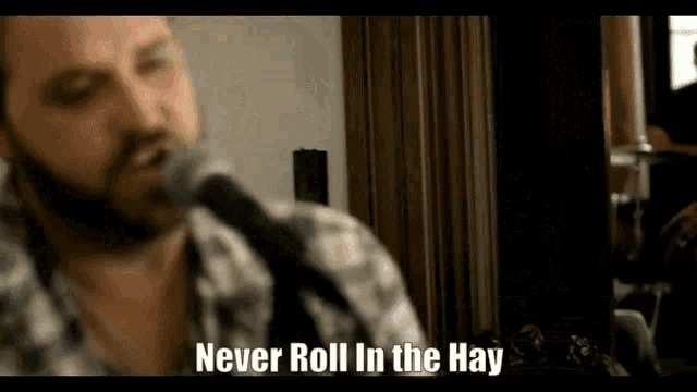 a man singing into a microphone with the caption never roll in the hay