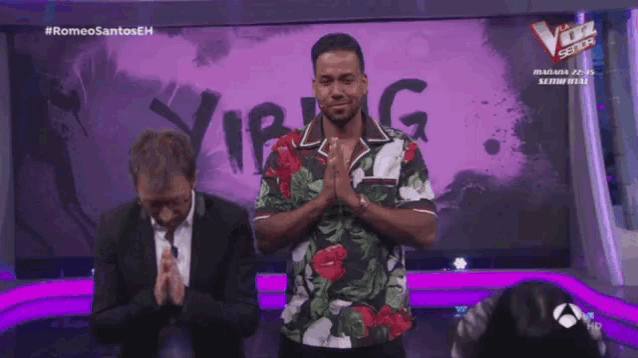 a man in a floral shirt is praying in front of a sign that says vip
