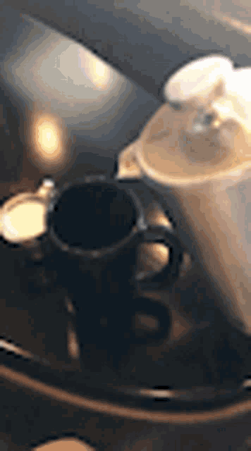 a cup of coffee sits on a table next to a pitcher