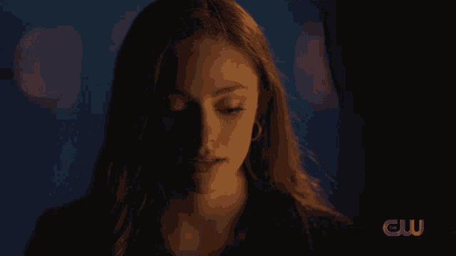 a close up of a woman 's face with the cw logo in the background