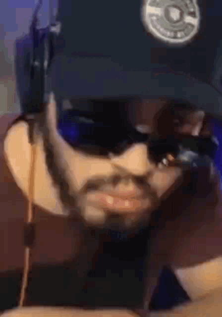 a man with a beard wearing a hat and sunglasses .