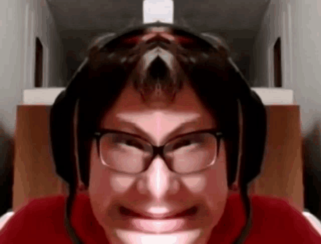 a man wearing glasses and headphones is smiling and making a funny face .