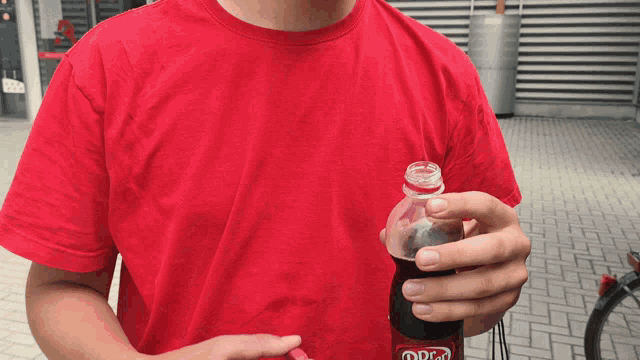 a man in a red shirt is holding a bottle of diet coke