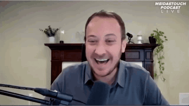 a man is laughing in front of a microphone during a podcast live