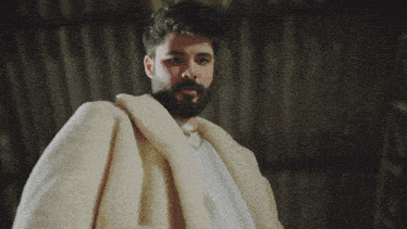 a man with a beard wearing a white coat is holding a sword