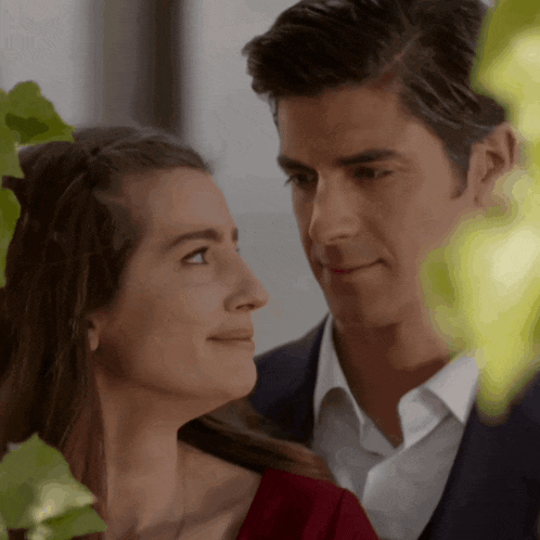 a man in a suit and a woman in a red dress are looking at each other
