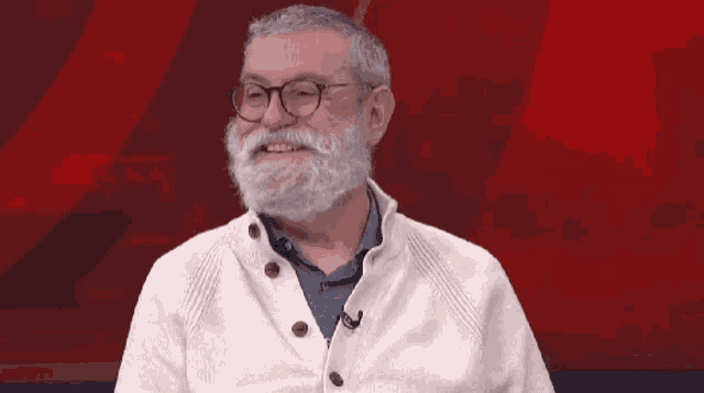 a man with glasses and a white beard is smiling