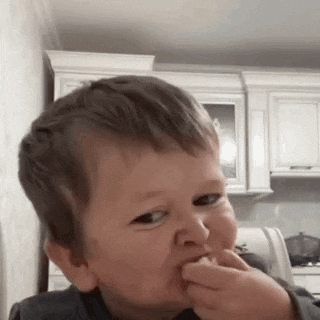 a young boy is making a funny face in a kitchen while eating something .