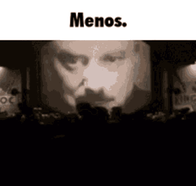 a man with a mustache is being shown on a large screen in a dark room .