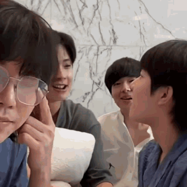 a group of young men are sitting on a couch and talking to each other .