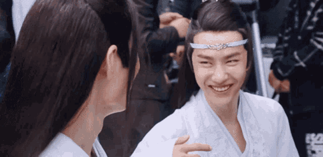 a man wearing a headband smiles while another man looks on