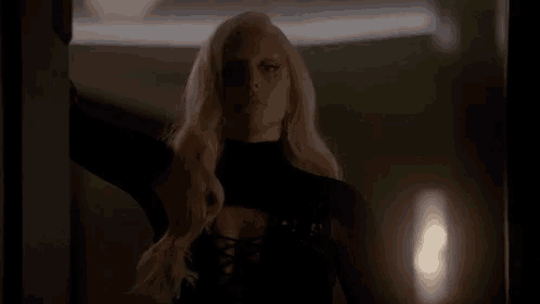 a woman with blonde hair is standing in a dark room .
