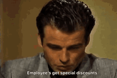 a man in a suit is sitting at a table with his eyes closed and says `` employee 's get special discounts '' .