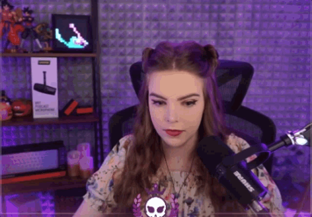 a woman sitting in front of a shure microphone in a purple room
