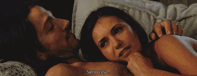 a man and a woman are laying in bed and the woman is saying seriously