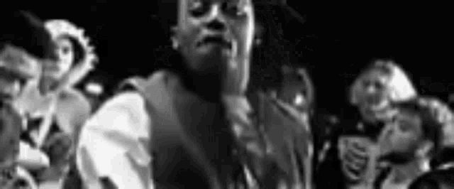 a black and white photo of a man in a suit standing in front of a crowd of people .