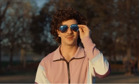 a man wearing sunglasses and a pink sweater