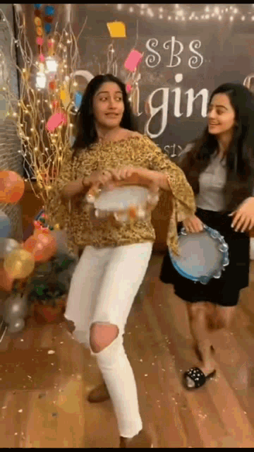two girls are dancing in front of a sbs sign