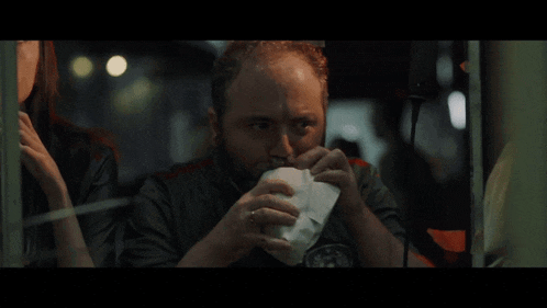 a man with a ring on his finger eating a hamburger