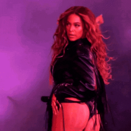 a woman in a black leather jacket is standing in front of a purple backdrop