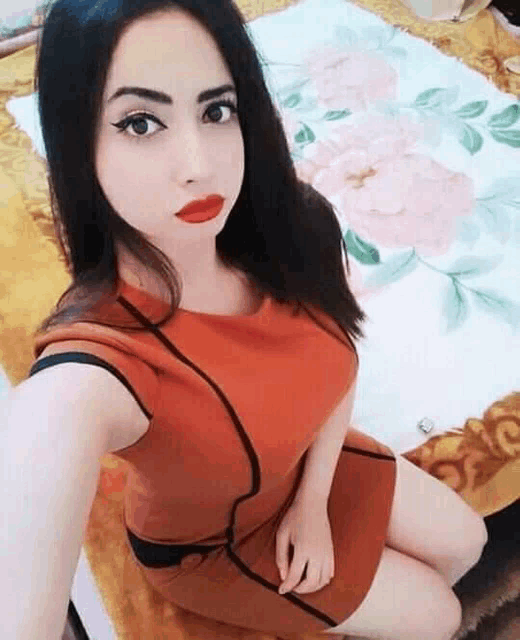 a woman is sitting on a bed taking a selfie .