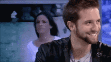 a man with a beard is smiling with a woman behind him .
