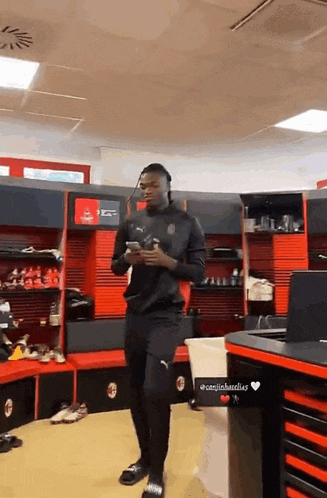 a man standing in a locker room looking at his phone with a sticker that says @canjinbandles