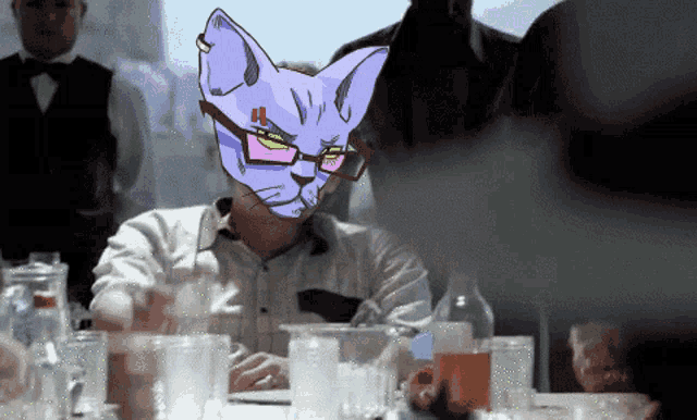 a man with glasses and a cat mask on his face sits at a table