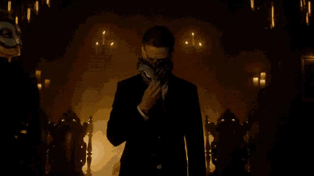 a man in a suit and tie has an owl mask on his face