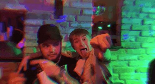 two men are posing for a picture and one of them is sticking out his tongue