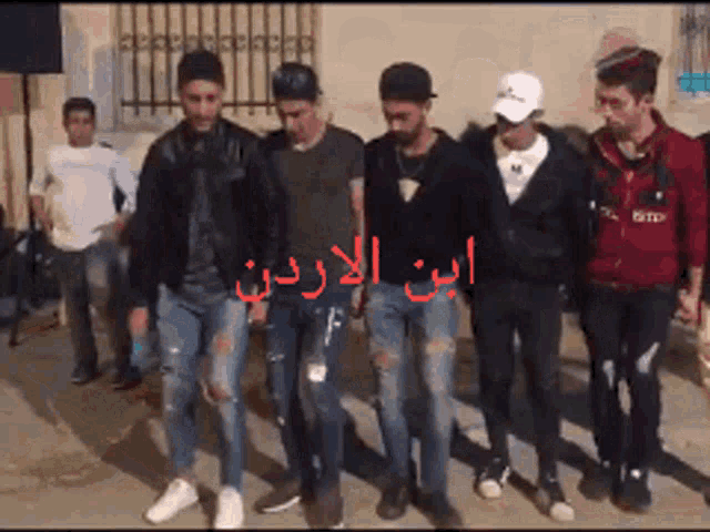a group of young men are walking in a line with arabic writing on the side