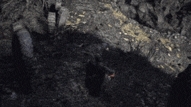 a man in a black robe is holding a torch in a cave .