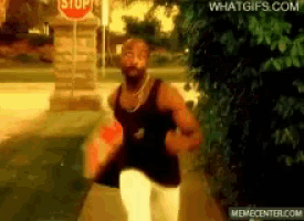 a man is running in front of a stop sign on a sidewalk