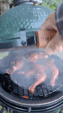 a person is cooking meat on a big green egg