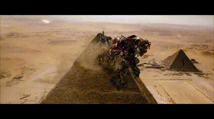 a group of transformers are standing on top of a pyramid in the desert