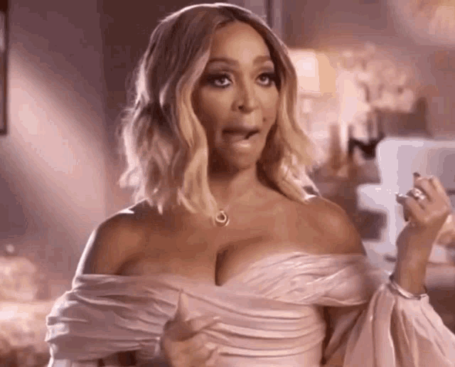 a woman in a pink off the shoulder dress is making a surprised face .