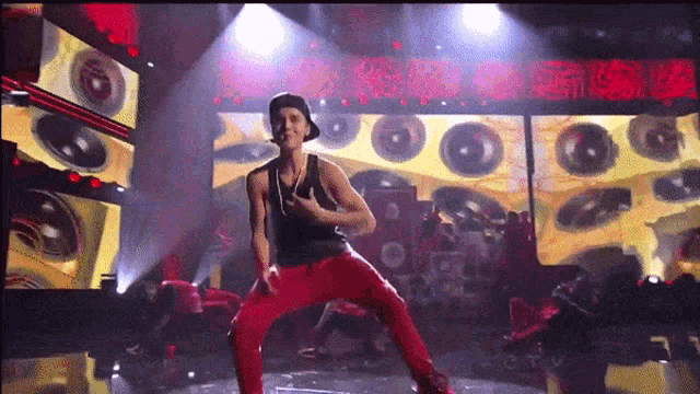 a man in a black tank top and red pants performs on a stage