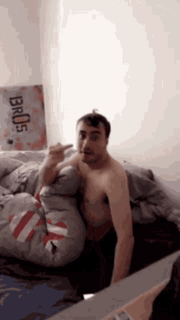 a shirtless man sits on a bed next to a sign that says bro 's