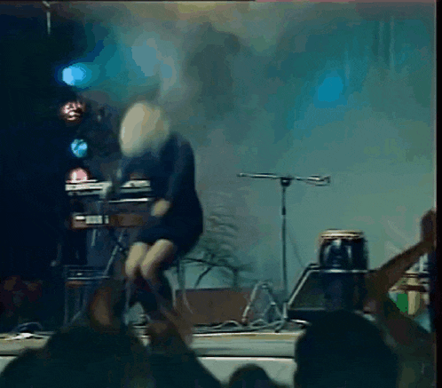 a woman in a black dress is dancing in front of a crowd