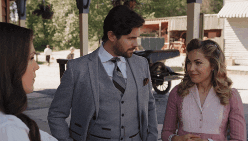 a man in a suit and tie stands next to a woman in a pink dress