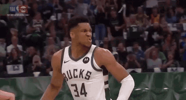 a basketball player wearing a bucks jersey is standing in front of a crowd during a game .
