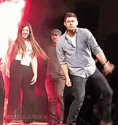 a man and a woman are dancing on a stage with red lights behind them .