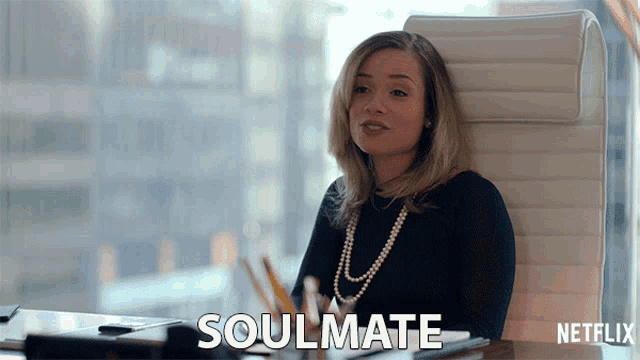 a woman sits at a desk with the word soulmate written on the screen behind her