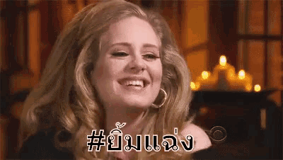 a woman is smiling in a room with candles in the background and the words in a foreign language .