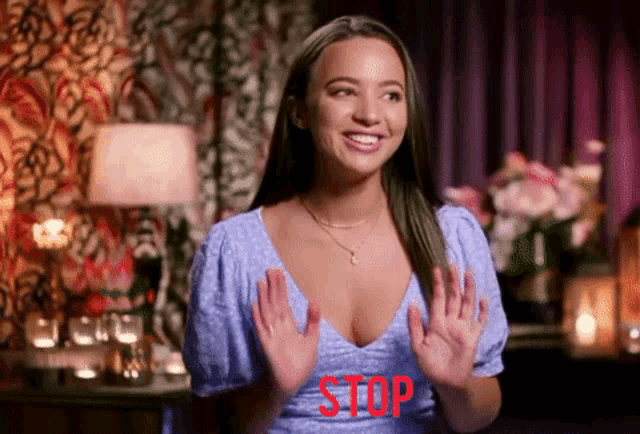 a woman in a blue dress says stop with her hands up