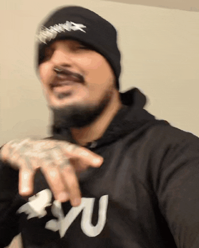 a man wearing a black hoodie and a black beanie has the letter u on his chest