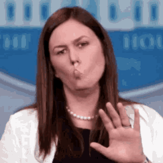a woman is blowing a kiss while holding her hand up in front of her face .