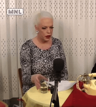 a woman in a leopard print dress is sitting at a table with a glass of water and a microphone .