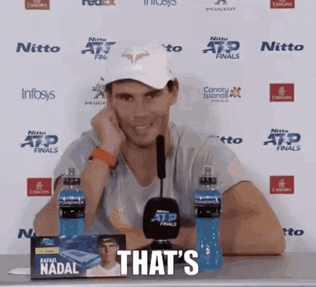 a man is sitting at a table with a microphone and bottles of powerade and says that 's